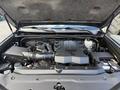 The image shows the engine bay of a 2021 Toyota 4Runner featuring a large V6 engine with various components including an air intake and battery