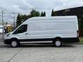 A 2021 Ford Transit van with a white exterior and black lower body is parked, featuring a tall and boxy shape with large rear doors and alloy wheels