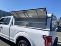 A white 2017 Ford F-150 with a raised truck bed cover revealing an empty storage area inside