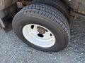 Close-up of a tire mounted on a white rim from a 2012 Ford Econoline featuring deep treads and visible wear on the rubber
