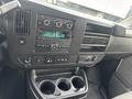 Interior dashboard of a 2022 GMC Savana featuring a radio with knobs and buttons air conditioning controls and a central console with cup holders