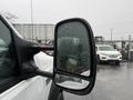 A close-up of the side mirror of a 2006 Ford F-450 showing water droplets on the surface of the glass