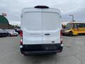 A white 2024 Ford Transit van viewed from the rear with the model name displayed on the back door
