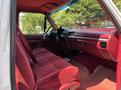 Interior view of a 1995 Ford F-250 showing red fabric seating and dashboard features with a steering wheel and gear shift visible