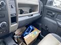 A 2011 Dodge Ram 5500 interior showing a dashboard with a storage compartment and a box containing a blue object and wires on the floor
