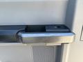 Close-up of a door handle on a 2017 Ford F-550 with a black plastic grip and a button for electronic door locking