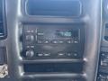 A dashboard display of a 2005 GMC C7500 Topkick featuring a radio with buttons and an analog clock showing 1100