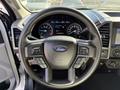 Black steering wheel of a 2021 Ford F-250 SD with controls and the Ford logo visible in the center
