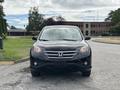 A black 2014 Honda CR-V is parked with its front view visible showcasing its sleek design and prominent Honda emblem on the grille