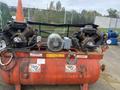 A red Baldor air compressor with two large motors and a warning cone on top