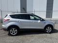 A silver 2014 Ford Escape parked with a sleek design featuring rounded edges and a sporty stance along with five alloy wheels