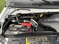 Close-up of the engine compartment of a 2017 Ford E450 showing various components including the battery hoses and fluid reservoirs