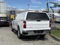A white 2019 Chevrolet Silverado 1500 pickup truck with a camper shell parked with a clean design and chrome accents