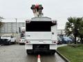 A 2020 International MV607 truck viewed from the rear with a mounted hydraulic lift and a red and white boom arm raised above