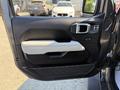 The image shows the interior door panel of a 2021 Jeep Gladiator featuring a black and gray color scheme with a door handle and controls for windows and locks