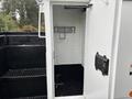 A 2013 Freightliner 114SD truck with an open storage compartment showing metal shelving and a hook inside