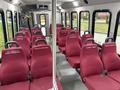 Interior view of a 2017 Ford E450 bus featuring multiple rows of red fabric seats with seatbelts and name tags on each seat
