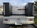 A 2015 Ford F-550 truck with a flatbed and a metal storage container in the center