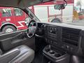 Interior view of a 2022 GMC Savana showing the dashboard steering wheel and seats with controls and storage compartments visible