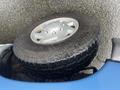 A 2006 Ford Econoline with a large silver wheel and rugged tire partially on its side