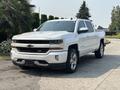 A white 2017 Chevrolet Silverado 1500 pickup truck with chrome accents and alloy wheels parked on a driveway