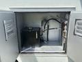 An open compartment of a 2011 Workhorse W62 displaying a black tank with attached hoses and fittings inside a metal structure