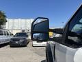 A 2019 Ford F-550 with large side mirrors is parked in a lot alongside other vehicles including a black SUV and a white van
