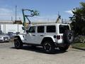 A 2021 Jeep Wrangler in white with a black spare tire mounted on the rear and rugged tires parked on a concrete surface