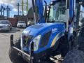 A blue 2010 New Holland T4050 tractor with black tires and a distinctive front grille is parked prominently in the foreground