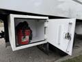 A storage compartment on a 2021 Freightliner M2 106 with a red bucket and chains inside