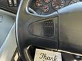 A close-up of the steering wheel of a 2013 International CE300 featuring a black leather grip and a control button on the side
