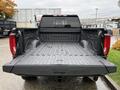 A 2022 GMC Sierra 3500HD showing an empty truck bed with a textured liner and wet surface