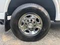 Close-up of a chrome wheel rim of a 2021 Chevrolet Express featuring five circular cutouts and the Chevrolet logo in the center with a black tire mounted on it