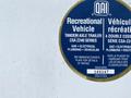 A circular label featuring information about a recreational vehicle with details on gas, electrical, plumbing, and vehicular specifications