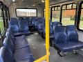 Interior seating of a 2020 Chevrolet Express bus with blue fabric seats arranged in rows and a yellow vertical pole for support