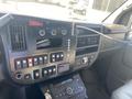 Dashboard of a 2011 Chevrolet Express with various buttons knobs and a central console featuring a digital display and exposed wiring