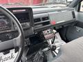Interior view of a 2002 GMC C7500 showing the dashboard with gauges buttons and gear shift along with a patterned floor mat
