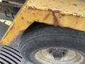 Close-up of a rusty edge of a yellow trailer with a black tire visible showing wear on the tread and the wheel hub in the center