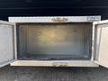 An open aluminum tool box with a diamond plate design revealing an empty interior