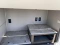 Two gray countertops inside an RV compartment with electrical outlets visible on the wall above