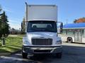 A 2011 Freightliner M2 106 truck facing forward with a white cargo box and prominent grill details