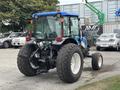 A blue and black 2009 New Holland T4020 tractor with large rear tires and an open cabin facing away from the viewer
