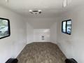 Interior of a 2025 Shuttle Office featuring smooth white walls and a wooden floor with two windows on the sides