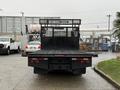 A 2015 Hino 195 flatbed truck with a black truck bed and a mesh safety screen at the back