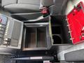 A 2020 Mercedes-Benz Sprinter 2500 interior featuring a console with buttons and a storage compartment with an open red box and multiple slots for organizing items