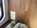 A wall-mounted electrical outlet next to a neatly folded green and white patterned blanket inside a 1976 GMC Motorhome