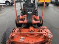 A 2015 Kubota F3990 with a front-mounted mower deck featuring a large cutting blade and two steering handles in the foreground