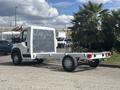A 2023 RAM Promaster 3500 chassis cab in white with a clear plastic cover over the driver's compartment and a flatbed design in the rear