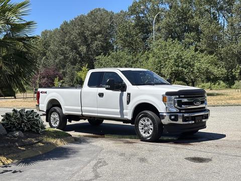 A white 2020 Ford F-350 Super Duty pickup truck parked with its cab facing forward and a spacious bed in the back
