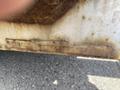 Close-up of a metal plate displaying the model and serial number of a 2008 Wells Industries Inc EW1422 equipment with visible rust and wear on the surface